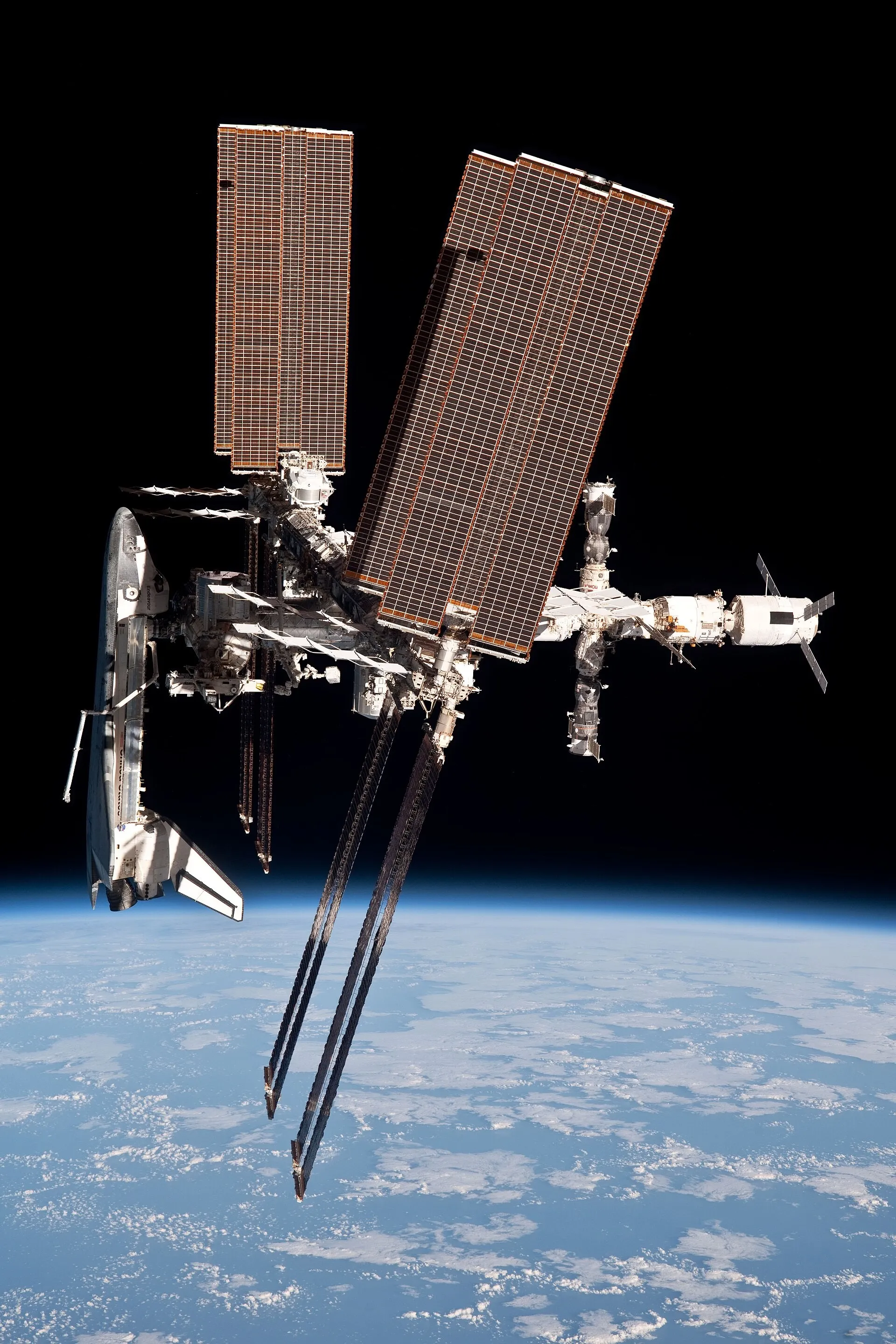 Endeavour docked to the International Space Station. The Shuttle's unique combination — a large crew, a cargo bay, a robotic arm, and the ability to bring things home — made it the vehicle that assembled and serviced the great structures of its era.
