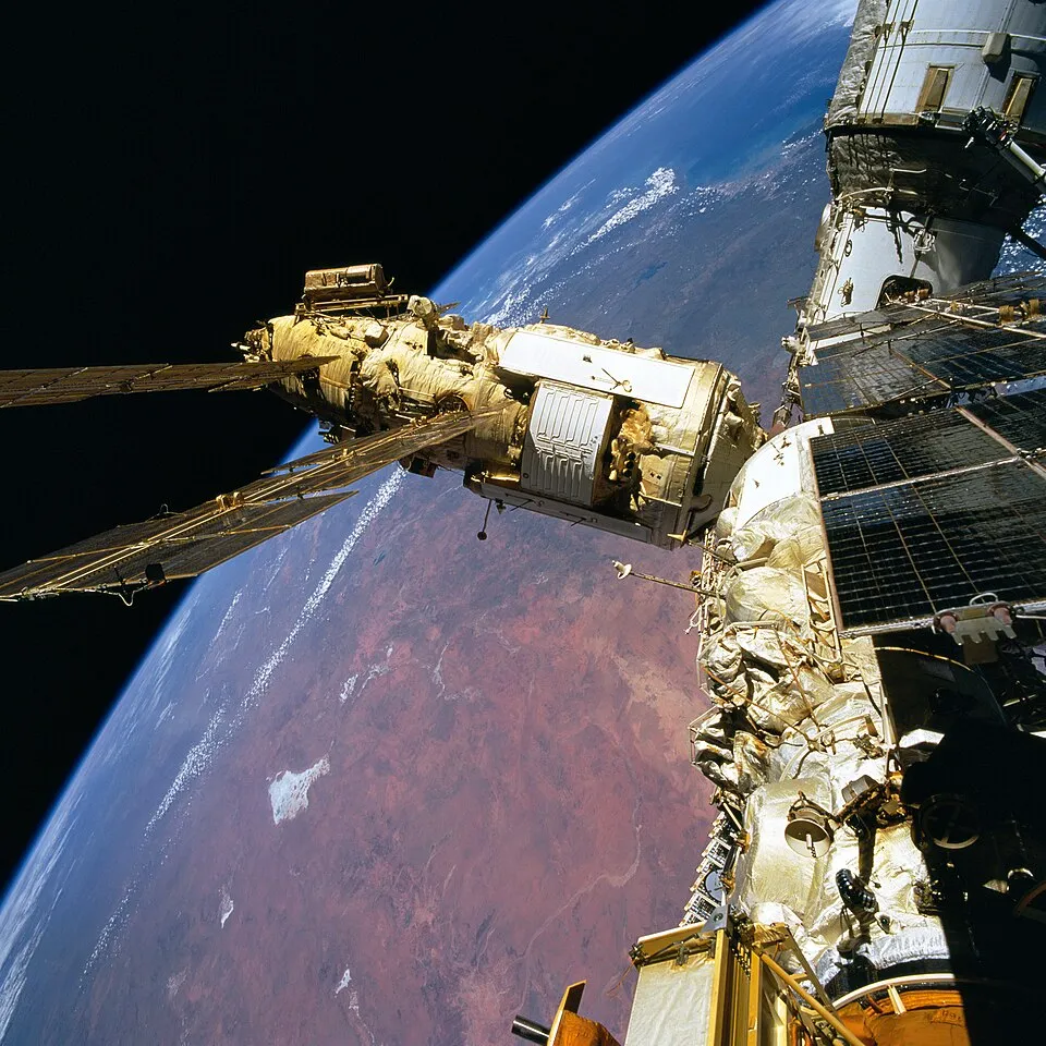 Mir under assembly, photographed from a visiting Space Shuttle — the core module with Kristall and the other modules attached. Building a large station from separately-launched pieces, in orbit, was itself the achievement.